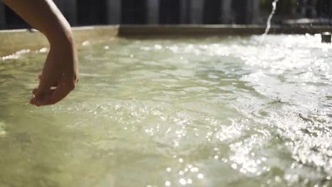 Woman-touching-and-splashing-water-in-fountain