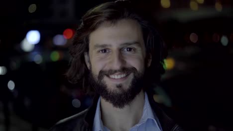 Hombre-guapo-sonriente-y-mirando-a-cámara-en-la-noche