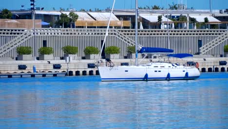 A-large-sailing-yacht-sails-along-the-pier-and-starts-mooring-in-the-seaport