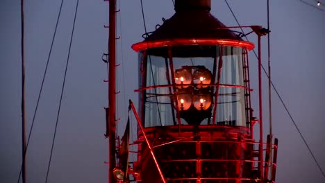 Rotating-lighthouse-at-dusk-in-a-harbor