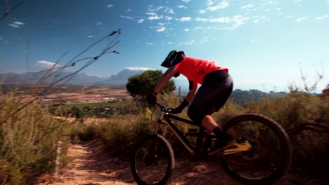 Mountain-biker-riding-downhill-on-a-cross-country-dirt-path