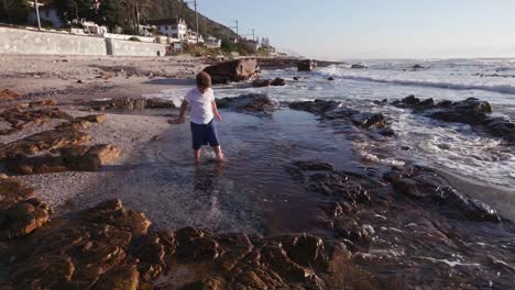 Junge-Erkundung-der-Fels-Schwimmbad-am-Strand-in-Kapstadt,-Südafrika