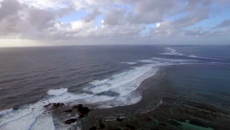 Aerial-view-of-water-line-of-seas-that-do-not-mix-against-blue-sky-with-clouds,-Mauritius-Island