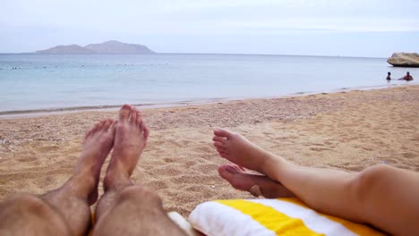 Beine-von-Menschen-am-Strand-Sonnenliege-liegen-in-der-Nähe-von-Meer