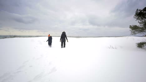 mother-and-kid-walking-on-beach-ontario-canada-in-winter-with-snow