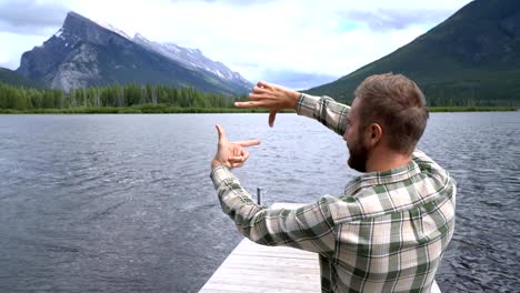 Young-man-standing-by-the-lake-framing-nature