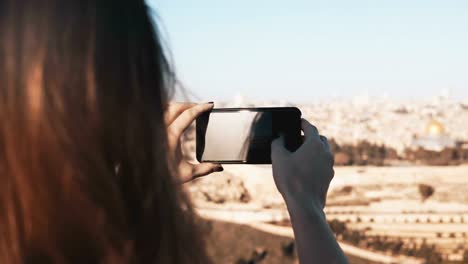 Mädchen-macht-Smartphone-Fotos-von-Jerusalem,-Israel.-Weibliche-Hände-halten-Telefon-an-einem-sonnigen-Tag.-Momente-festhalten.-4K