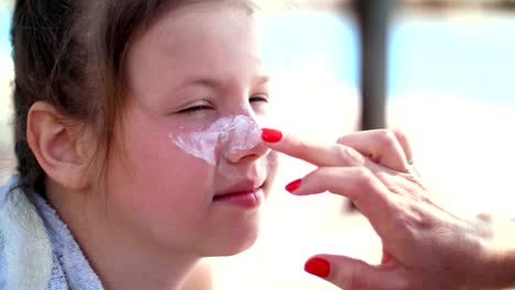 close-up,-the-child,-girls,-severe-sunburn-on-the-face.-Mom-smears-places-of-burns-abundantly-with-a-special-cream.-Mother-applying-sun-protection-cream-to-her-daughter-face