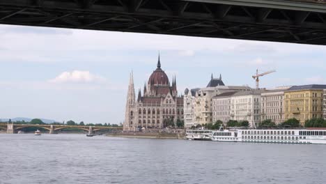 The-Hungarian-Parliament-Building-landscape-with-sightseeing-ship-on-the-Danube-in-Budapest,-Hungary-in-the-afternoon.