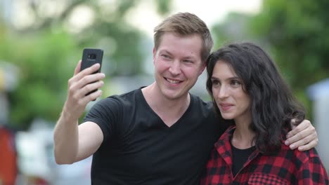 Young-couple-taking-selfie-together-outdoors