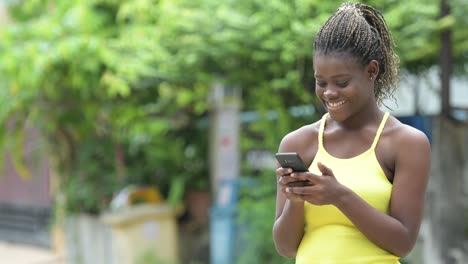 Young-happy-African-woman-using-phone-outdoors