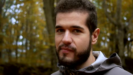 young-attractive-man-in-the-forest-jokes-and-smiles-at-the-camera