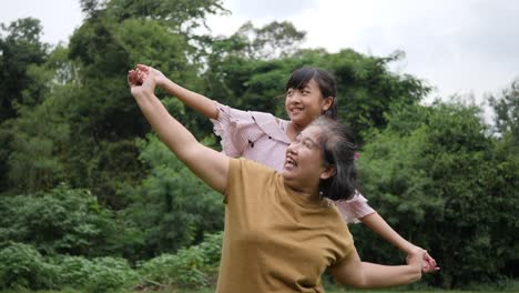 Slow-motion-of-Happy-grandmother-with-granddaughter-playing-in-the-park