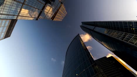 Bottom-up-Blick-auf-rotierende-Wolkenkratzer-und-fliegenden-Wolken,-Zeitraffer,-hyper-Zeitraffer