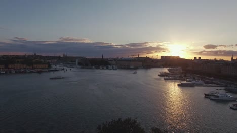 View-of-Stockholm-city-at-sunset,-ferry-boat-passing-by-on-river