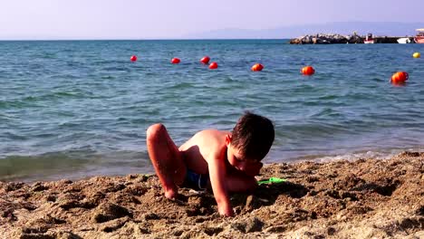 Kleiner-Junge-am-Meeresstrand-im-Sand-spielen