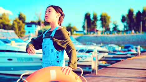 Girl-poses-with-a-life-buoy-on-a-wharf-of-boats-and-yachts