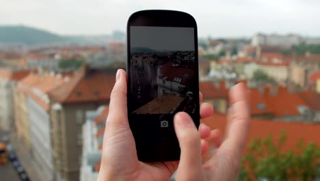 vista-cercana-de-manos-femeninas-con-smartphone-y-tomar-fotos-de-edificios-de-techo-rojo-en-Praga