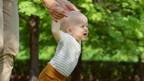 Mutter-hilft-Baby-die-ersten-Schritte-im-freien