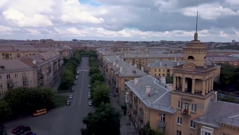 Drone-flight-near-the-old-style-tower-with-factory-on-the-background