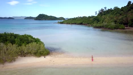 Drone-shot-aerial-view-of-Young-woman-relaxing-on-tropical-beach-arms-outstretched-enjoying-freedom-in-the-Philippines-Islands.-People-travel-luxury-vacations-destinations-concept