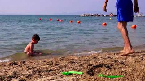 Padre-con-un-hijo-pequeño-en-la-playa-de-la-mar,-Grecia