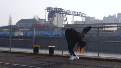 Young-Woman-Dancing-on-Riverside-Walkway