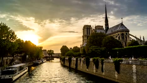 Timelapse-of-Paris-at-sunset,-with-boats-passing-in-front-of-Notre-Dame-de-Paris-cathedral-on-the-Seine-River