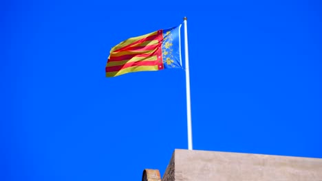 Flagge-von-Valencia-(Spanien)-fliegt-über-das-Gebäude-gegen-den-blauen-Himmel