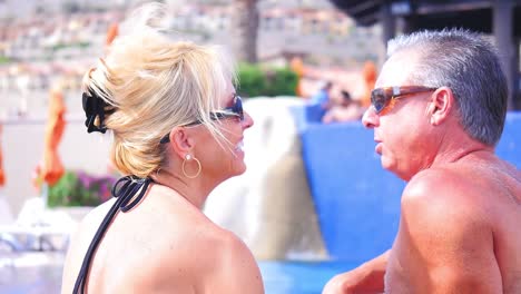 Close-up-of-an-older-couple-sitting-by-a-pool