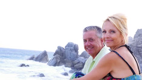 Una-Pareja-de-ancianos-de-estar-en-la-playa-y-mirando-el-olas-y-luego-sonriendo-a-la-cámara