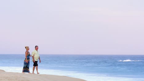 Una-Pareja-de-ancianos-sosteniendo-las-manos-y-caminar-en-la-playa-y-abrazar