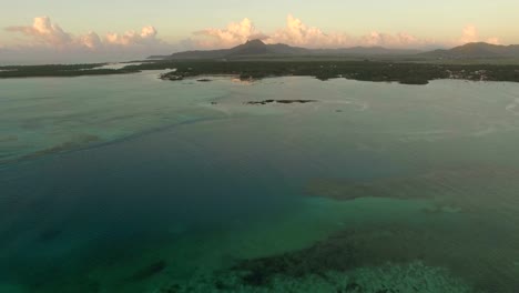 Aerial-view-of-ocean-blue-water-with-waves,-corals-and-water-plants,-camera-moving-to-coast,-Mauritius-Island