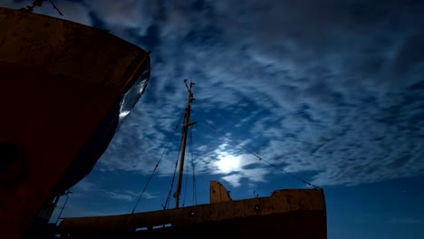 Restos-de-antiguos-barcos-en-la-orilla-del-río-frente-a-sol-de-timelapse-de-nubes-que-fluye.