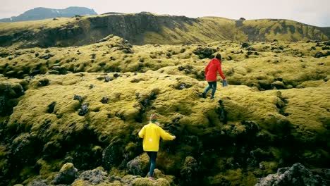 Aerial-view-of-the-two-woman-walking,-hiking-on-the-lava-field-in-Iceland.-Tourists-falls-down-on-the-soft-moss