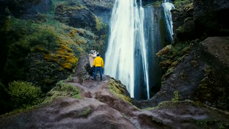 Aerial-shot-of-group-of-tourists-standing-on-top-of-cliff-near-the-Gljufrabui-waterfall-in-Iceland-and-enjoying-the-view