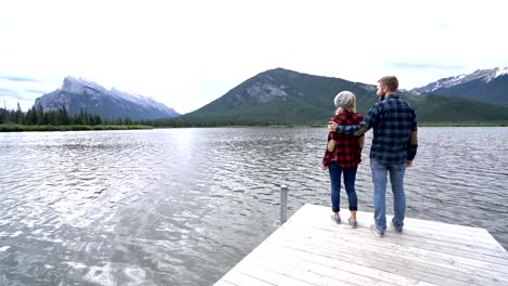 Pareja-joven-en-el-lago-en-Canadá,-brazos-extendidos-por-la-libertad