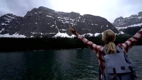 Brazos-de-la-chica-extendidos-por-lago-de-la-montaña