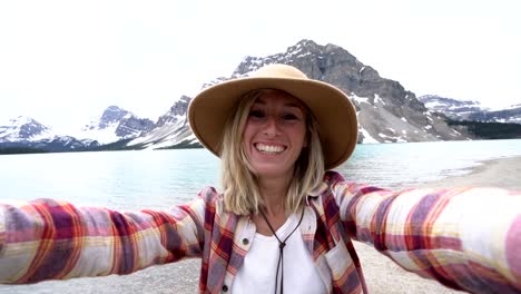 Young-woman-travelling-in-Canada-takes-selfies-by-stunning-mountain-lake-scenery