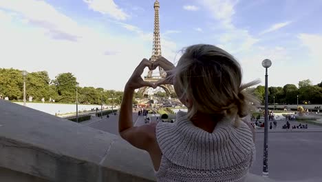 Young-woman-making-heart-shape-on-the-Eiffel-Tower,-loving-the-city--France