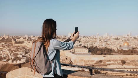 Tourist-girl-takes-photos-of-old-town-Jerusalem.-Girl-with-backpack-walks-to-skydeck-edge.-Capturing-moments.-Israel-4K