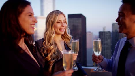 Multi-ethnischen-Kollegen-mit-Champagner-bei-Sonnenuntergang-auf-der-Dachterrasse