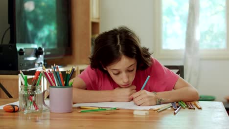 young-girl-sitting-at-the-table-drawing-with-colored-pencils