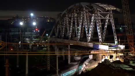 The-construction-of-a-steel-bridge-and-night-movement-of-trains-on-a-railway-junction