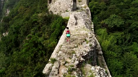 Luftaufnahme-des-jungen-Fitness-Frau-Trailläufer-läuft-oben-auf-der-Mauer