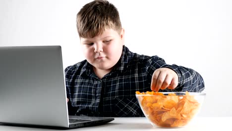 Young-fat-boy-eats-chips-and-and-plays-on-a-laptop-50-fps