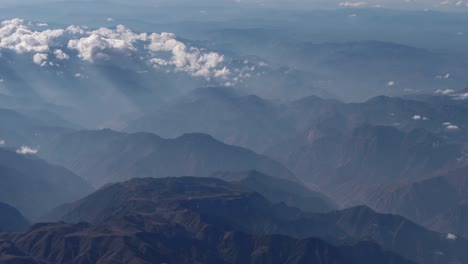 Beautiful-view-through-airplane-window,-airplane-flying-above-city-in-mountains