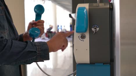 Asian-man-using-public-landline-payphone-telephone-inside-the-international-airport.