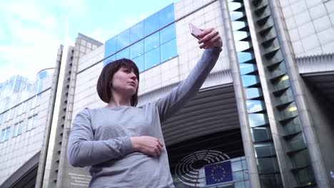 Lady-tourist-make-selfie-on-smartphone-near-the-European-Parliament-in-Brussels.-Belgium.-slow-motion