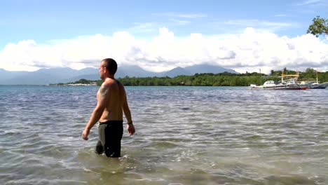 Un-hombre-en-shorts-está-caminando-en-el-mar